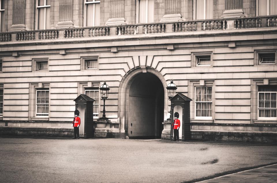 Guardias reales con casaca roja y gorro de piel ante la fachada del Palacio de Buckingham en Londres