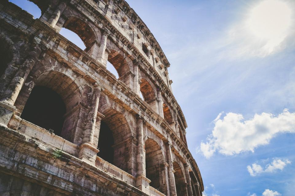Fachada exterior del Coliseo de Roma con sus arcos de piedra recortados contra un cielo azul